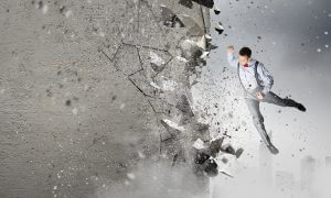 Emotional businessman breaking stone wall with karate punch